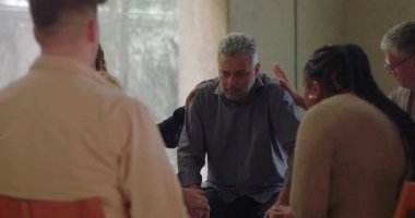 Katılımcılar ellerini sırtına ve kollarına koyup hassas anlarında rahatlık sunarken grup terapi üyelerinden duygusal destek alıyor.