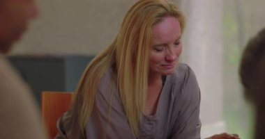 Erkek duygusal terapi seansında kafa kafaya otururken yanındaki kadın elini sessiz ve merhametli bir ortamda tutarak nazik bir destek sunuyor.