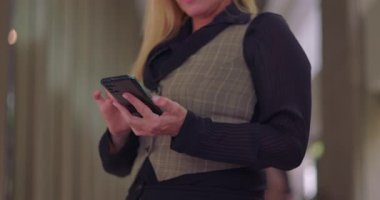 Ofis koridorunda ekranı kontrol ederken iki elinle akıllı telefon tutan iş kadınını kapat.