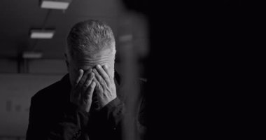 Modern ofis yönetim kurulundaki yoğun iş krizi sırasında dramatik ışıklandırmada elleri alnında sıkıntılı bir yönetici.