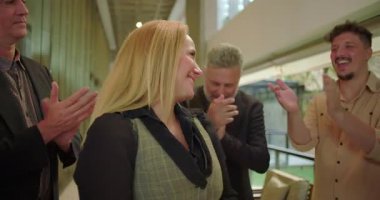 Ofis koridorundaki meslektaşlarından gülümseyen kadın profesyonel alkış alan çeşitli iş adamları, modern iş yerinde takdir ve destek gösteriyorlar.