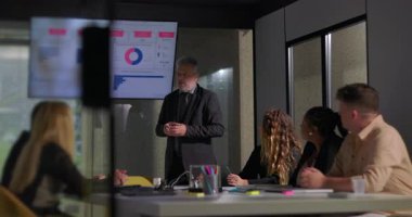 Kurumsal yönetici, kurul odasındaki renkli grafik ve çizelgeler gösteren dikkatli meslektaşlarına rapor verilerini açıklıyor