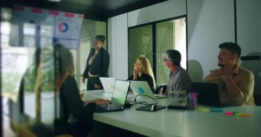 İş sunumu yaptıktan sonra gülümseyen Afro-Amerikalı sunucu meslektaşları takım ortamında olumlu yanıt verirken