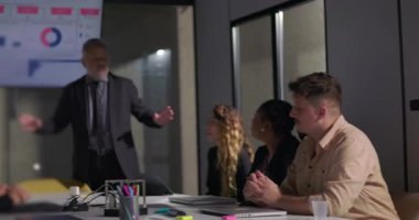 Şirket yöneticisi, modern yönetim kurulundaki toplantı sırasında geniş ekran ekran ile bağlı ekibe anahtar veri içgörülerini sunar.