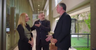 İşletme müdürü modern ofis koridorunda takım üyelerini sunar, mesleki tanışma sırasında iş arkadaşları buluşur ve el sıkışır.