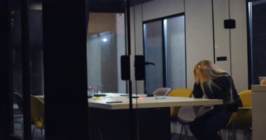 Bunalmış iş kadını konferans masasında tek başına oturuyor, yüzü ellere gömülü, yoğun işyeri stresi ve baskı altında duygusal gerginlikle başa çıkıyor.
