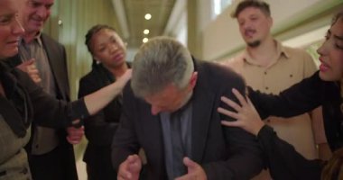 Duygusal çalışma saatlerinde ofis koridorunda destekleyici meslektaşları tarafından teselli edilirken sıkıntılı erkek profesyonellerin acı ve endişe göstermesi