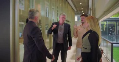 Mutlu ofis ekibi koridorda beşlik çakıyor, iş arkadaşları ortak başarıyı coşkulu bir takım çalışması ve profesyonel ortamdaki motivasyon jesti ile kutluyor.