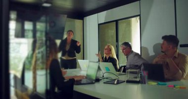 Meslektaşları modern ofis konferans odasında gözlem yaparken Afrikalı Amerikalı iş kadını takım sunumu sırasında soruları yanıtlıyor