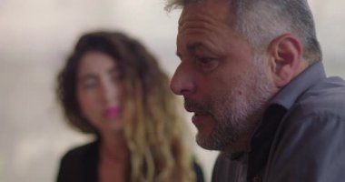 Erkekler terapi seansı sırasında duygularıyla konuşur, odaklanmış bakışlarla daireler çizer diğerleri sessizce dinler, kapalı alan ortamını destekler.