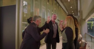 Neşeli iş grubu kapalı alanda beşlik çakıyor, iş arkadaşları takım başarısını ve işbirliği içindeki profesyonel atmosferde birlik olduğunu kabul ediyor