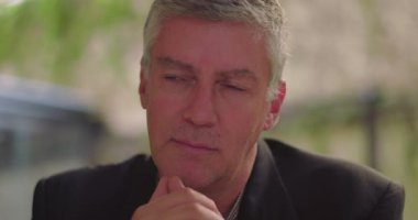 Ofisteki orta yaşlı adamın yakın plan fotoğrafı. İnce bir gülümseme ile yan yan bakıyor. Umut verici bir yansıma ya da iç iyimserlik belirtileri gösteriyor.