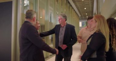 Modern ofis koridorlarında iş adamları gelişigüzel konuşuyor, çeşitli iş arkadaşları bir arada duruyor ve gayri resmi iş yerinde rahatça sohbet ediyorlar.