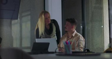 Modern ofis konferans odasındaki çalışma oturumunda erkek meslektaşına yardımcı olan kadın yönetici.