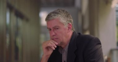 Ofis salonunda kıt kanaat geçinen orta yaşlı bir adam sessizce duygusal ya da derin düşüncelere dalmış.