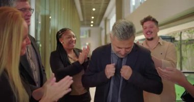 Ofis koridorundaki destekleyici meslektaşlarından alkış alırken gülümseyen müteşekkir erkek profesyonel, tanınma ve takdir anı
