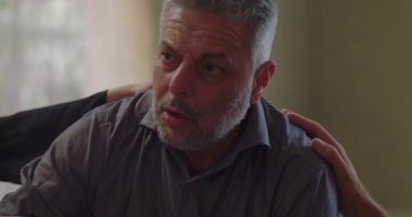 Terapi seansında, grup üyeleri sakin bir duygusal ortamda rahatlık ve destek sağlarken, erkekler el ele tutuşuyorlar.