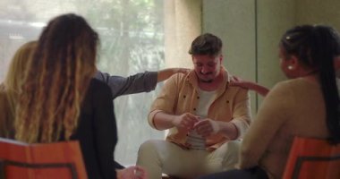 Grup terapisinde duygusal çöküntüye uğramış bir adam, destekleyiciler arasında duygusal rahatlama ve duygusal çöküntü anında kafa kafaya oturuyor.