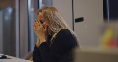 Baskı, baskı ve yorgunluk belirtileri gösteren, ofis masasında başını kollara gömen, ezilmiş orta yaşlı bir kadının yakın çekimi.