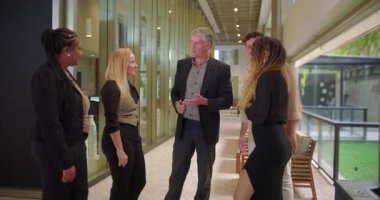 Modern ofis koridorunda takım üyelerini tanıtan yönetici, çeşitli profesyonel gruplar gayri resmi tanışma ve iş yeri sohbeti için kuyrukta bekliyor