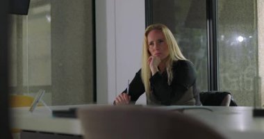 Modern ofis yerinde yalnız başına oturan bir kadın endişeli görünüyor, iş günlerinde bir karar veriyor ya da düşünüyor gibi görünüyor.