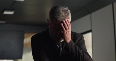 Kurumsal gerileme sırasında gergin ofis toplantısında saçlarını yolarken sinirli iş adamı duygularını zapt ediyor.