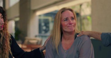 Terapi seansında grup üyeleri tarafından teselli edilen ağlayan bir kadın, acılarını dile getirirken şefkat ve destek görüyor.