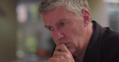 Orta yaşlı bir adamın dinlenme odasında baş başa dinlenmesi derin düşüncelere dalması ve sessiz profesyonel ortamda karar vermeye odaklanması.