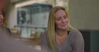 Grup terapi seansında duygusal hikâyeyi paylaşan kadın, erkek grup üyesi güven verici bir şekilde omuz omuza verip, incinebilirliğini gözyaşlarıyla ifade ederken,