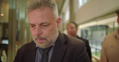 Takım elbiseli olgun iş adamının endişeli bir ifadeyle ofis koridorunda yüzünde gözle görülür bir ızdırap ve duygusal gerilimle dikilmesi.