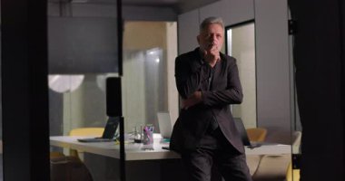 Üst düzey yönetici toplantı sırasında elleri çenesinde ve derin düşüncelere dalmış bir şekilde toplantı odasında tek başına duruyor.