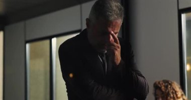 Düşünceli bir işadamı, şirket tartışması sırasında ciddi kararları değerlendirirken el pençe divan duruyor.