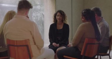 Grup terapisinde konuşan genç bir kadın şefkatli grup üyelerinden oluşan bir çemberde otururken kişisel öyküsünü savunmasızlıkla paylaşıyor.