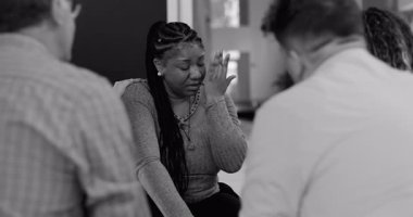 Terapi sırasında ağlayan bir kadın, dayanışma grubu üyelerinden hassas dokunuşlar alıyor derin bir hassasiyet anında ve empati paylaşımı, siyah-beyaz