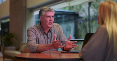 Erkek, ofis toplantısı sırasında iş fikirlerini aralarında dizüstü bilgisayarla sunarken anlamlı bir şekilde hareket ediyor.