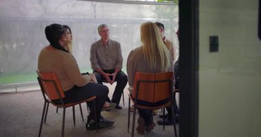 Çemberde oturan çeşitli kişilerle terapi grubu oturumu, katılımcılar kapalı alanlarda yapılan güdümlü duygusal destek toplantısı sırasında paylaşım ve dinleme