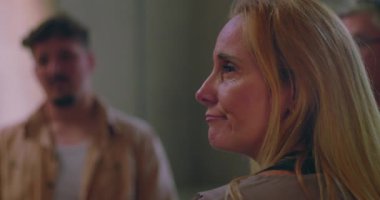 Terapi çemberinde konuşurken destek grubuna bakan kadın, bağlantı ve güven anında empati ile dinleyen katılımcılar