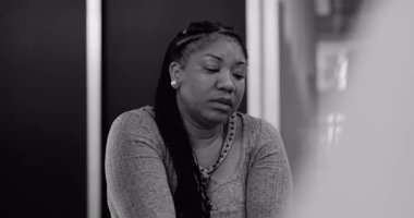 Duygusal rahatlama sonrası sessizlik içinde oturan kadın terapi seansında grup ile birlikte acıyı yansıtıyor.