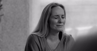 Grup terapisi sırasında ağlayan bir kadın, incinebilirlik ve yansıma anında derin acıları ifade ederken, siyah ve beyaz.