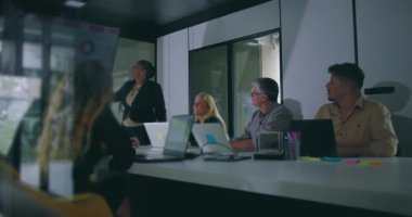 Modern ofis konferans odasında kurumsal toplantı sırasında ilgili meslektaşlarına anahtar verileri sunan Afrikalı Amerikalı iş kadını.