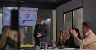 Modern ofis yönetim kurulu toplantısında başarılı bir sunumdan sonra takım liderini alkışlıyor.