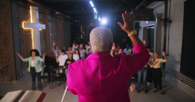 Papaz, ibadet eden ellerini kaldırarak cemaate önderlik ediyor, çeşitli Hıristiyan cemaati modern evanjelik kilisesinde ibadet ve övgüye katılıyor.