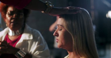 Vaiz, eli başının üzerinde olan sarışın kadını kutsadı. Ruhani tören, duygusal tapınma, sadakat ve çeşitli Hıristiyan cemaatlerine olan inanç süresince sakin bir ifade.