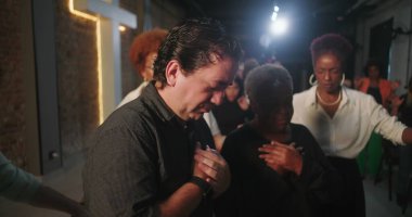 Duygusal dualarda ellerini göğsüne koyan çeşitli insanlar, ibadet sırasında inançla derin bir bağ, Hıristiyan cemaati, manevi birlik, arka planda geçiş.
