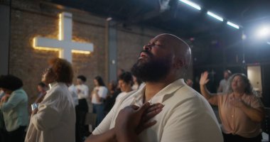 Yürekten ibadet eden bir adam, arka planda parlayan bir haç, kutsal kilisede derin manevi yansıma, inanç ve duygusal bağlantı.