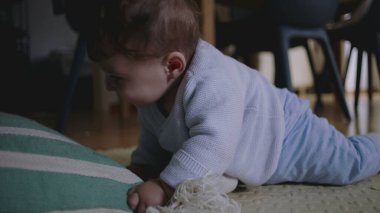 Bebek yerde yatıyor, çizgili bir yastığa uzanıyor, hayal kırıklığı ve öfke belirtileri gösteriyor, dokunarak oynamaya çabalıyor, hareket becerilerini geliştiriyor..