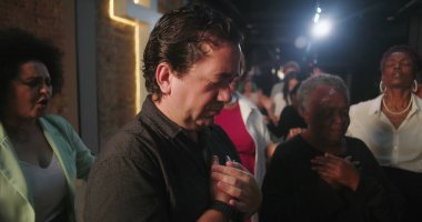 Duygusal dualarda ellerini göğsüne koyan çeşitli insanlar, ibadet sırasında inançla derin bir bağ, Hıristiyan cemaati, manevi birlik, arka planda geçiş.