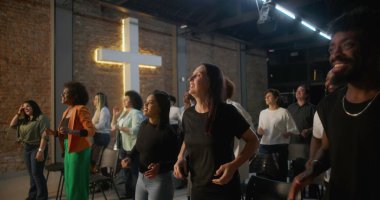 Kilisede ibadet sırasında alkışlayan ve gülümseyen çeşitli insanlar, arka planda parlayan haç, neşe, birlik ve ruhsal bağlantı ifadeleri