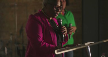 Afrika kökenli bir kadın vaaz veriyor. Evanjelik kilise toplantısı sırasında, mikrofon tutarken, güçlü vaazlar verirken, cemaate ruhani rehberlik ederken.