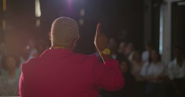 Afrika kökenli bir kadın vaaz verirken cemaat ibadete daldı. Evanjelik kilise toplantısı sırasında, övgüler ve bağlılıkla el kaldırıldı.